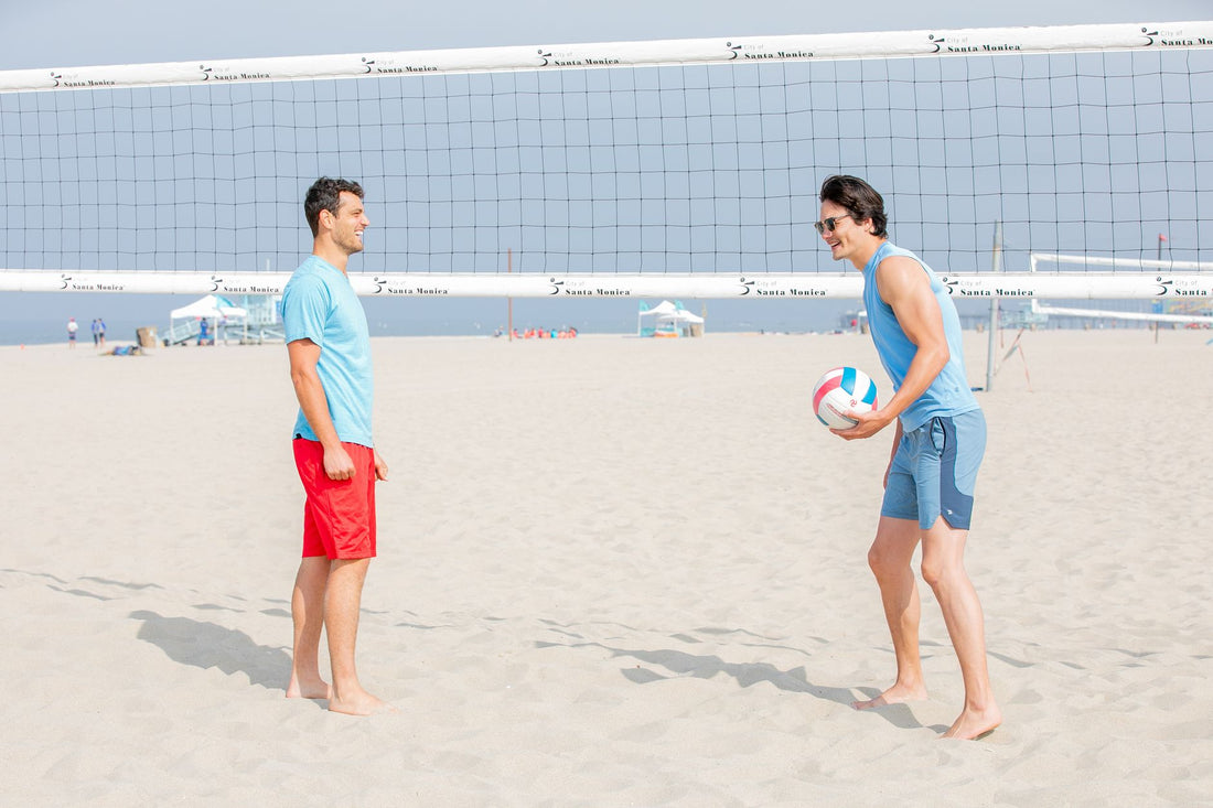 Due giocatori di beach volley maschile a muro sulla sabbia durante un'azione di gioco